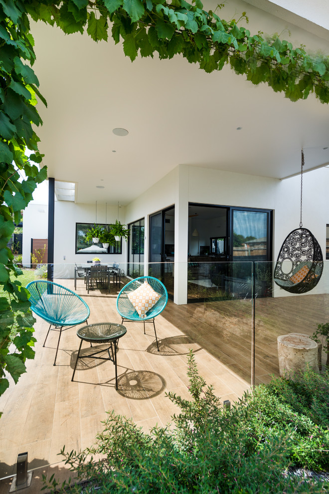 Design ideas for a contemporary backyard patio in Melbourne with tile and a roof extension.