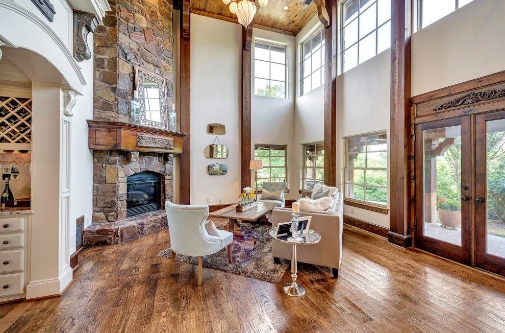 Photo of an expansive country formal living room in Dallas with medium hardwood floors, a standard fireplace, a stone fireplace surround, beige walls and no tv.