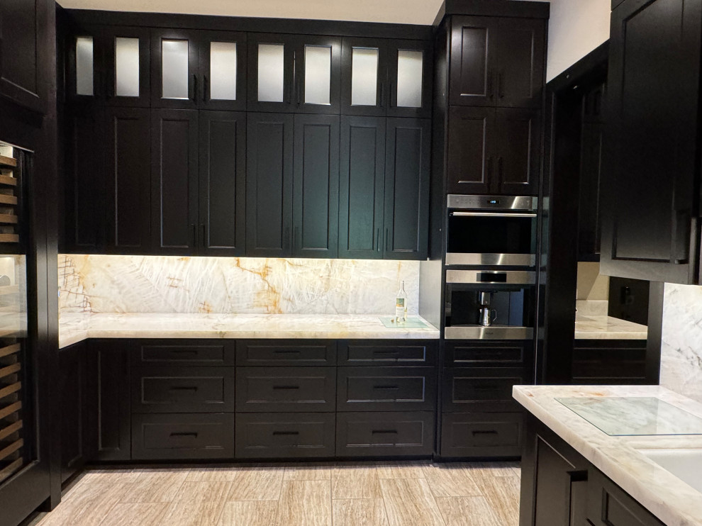 Kitchen pantry - large transitional l-shaped porcelain tile and beige floor kitchen pantry idea in Phoenix with an undermount sink, shaker cabinets, dark wood cabinets, quartzite countertops, beige backsplash, stone slab backsplash, paneled appliances, an island and beige countertops