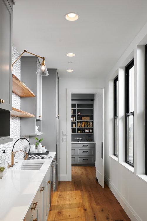 Photo of a country single-wall separate kitchen in Portland with an undermount sink, recessed-panel cabinets, grey cabinets, grey splashback, stainless steel appliances, medium hardwood floors and white benchtop.