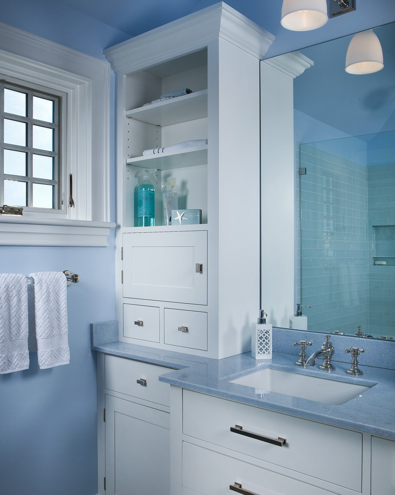 This is an example of a mid-sized beach style master bathroom in Portland Maine with beaded inset cabinets, white cabinets, a corner shower, blue tile, green tile, glass tile, blue walls, pebble tile floors, beige floor, a hinged shower door and blue benchtops.