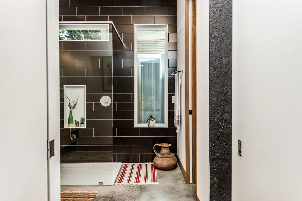This is an example of a mid-sized eclectic master bathroom in Houston with flat-panel cabinets, light wood cabinets, a curbless shower, a two-piece toilet, black tile, porcelain tile, white walls, concrete floors, a vessel sink, concrete benchtops, grey floor, an open shower, grey benchtops, a laundry, a single vanity, a floating vanity and wood.