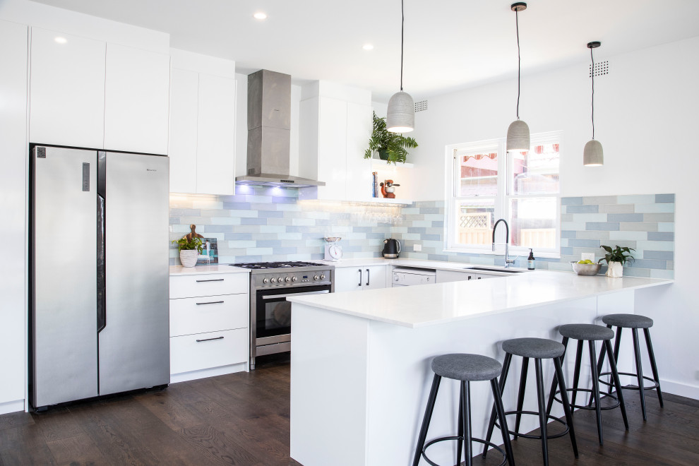 Design ideas for a large contemporary u-shaped open plan kitchen in Sydney with an undermount sink, white cabinets, quartz benchtops, multi-coloured splashback, subway tile splashback, stainless steel appliances, dark hardwood floors, with island, brown floor and white benchtop.