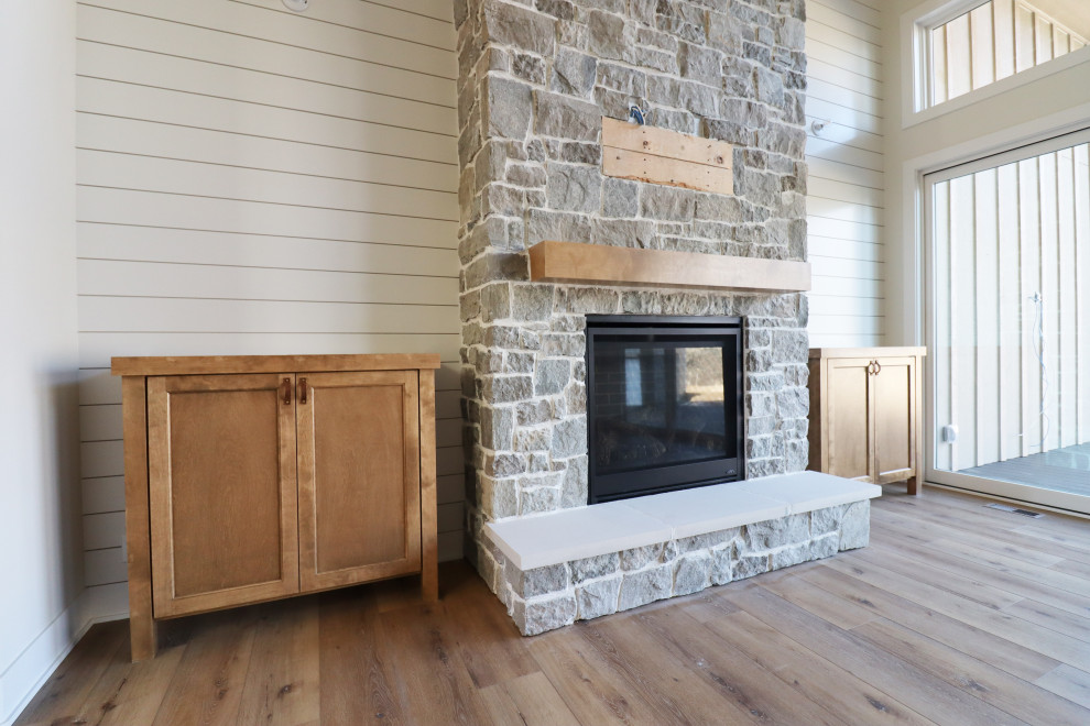 Exemple d'un salon chic ouvert avec une cheminée standard, un manteau de cheminée en pierre, un téléviseur fixé au mur et du lambris de bois.