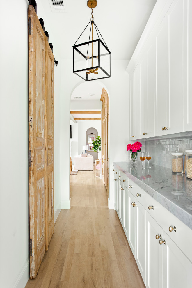 Idéer för stora vintage vitt kök, med en undermonterad diskho, skåp i shakerstil, vita skåp, marmorbänkskiva, vitt stänkskydd, stänkskydd i marmor, integrerade vitvaror, ljust trägolv, en köksö och brunt golv