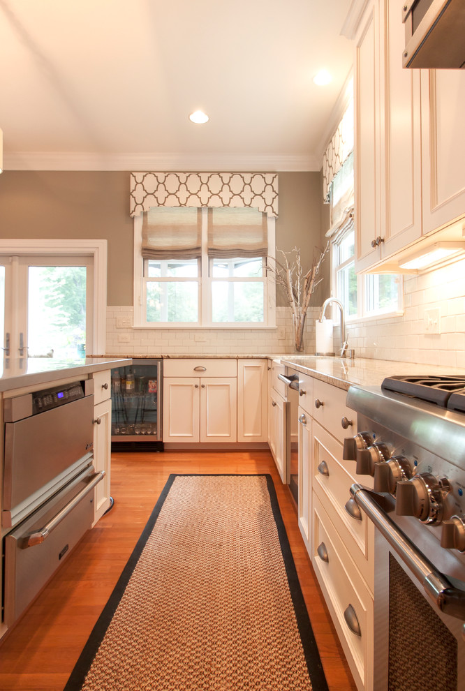 Inspiration for a large transitional medium tone wood floor kitchen remodel in DC Metro with an undermount sink, white cabinets, granite countertops, white backsplash, ceramic backsplash, stainless steel appliances and two islands