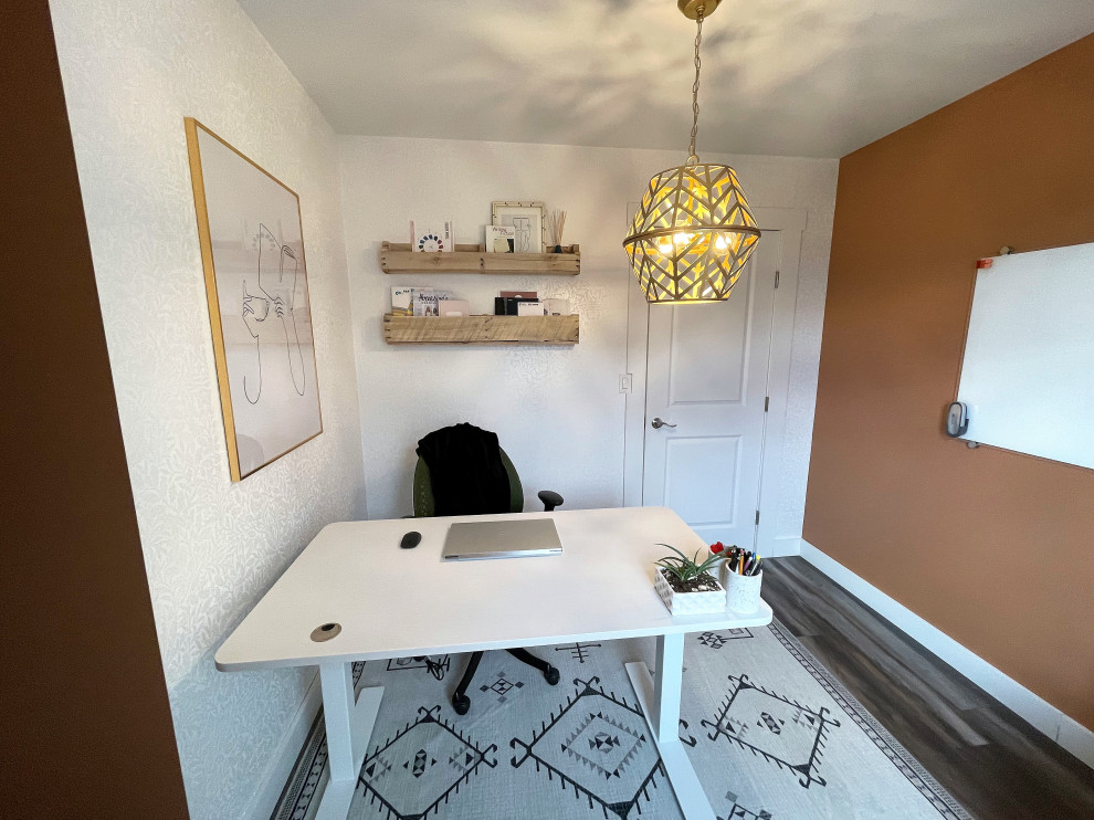 Kleines Landhausstil Arbeitszimmer ohne Kamin mit oranger Wandfarbe, Laminat, freistehendem Schreibtisch, grauem Boden und Tapetenwänden in Sonstige