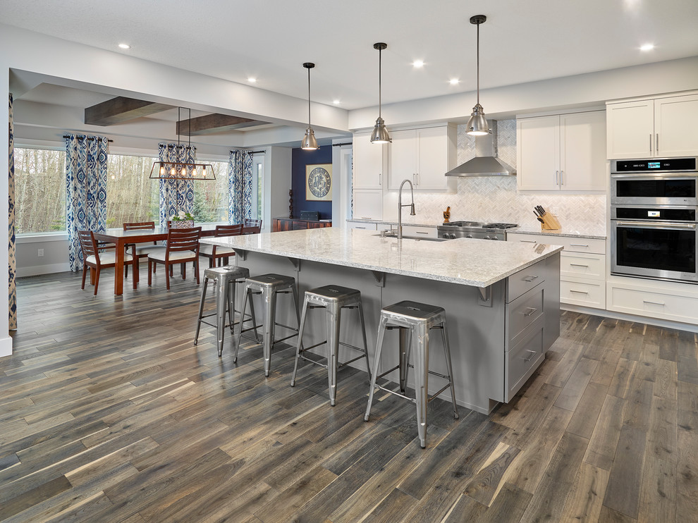 Example of a mid-sized transitional galley medium tone wood floor and brown floor eat-in kitchen design in Edmonton with an undermount sink, louvered cabinets, white cabinets, quartz countertops, white backsplash, ceramic backsplash, stainless steel appliances, an island and white countertops