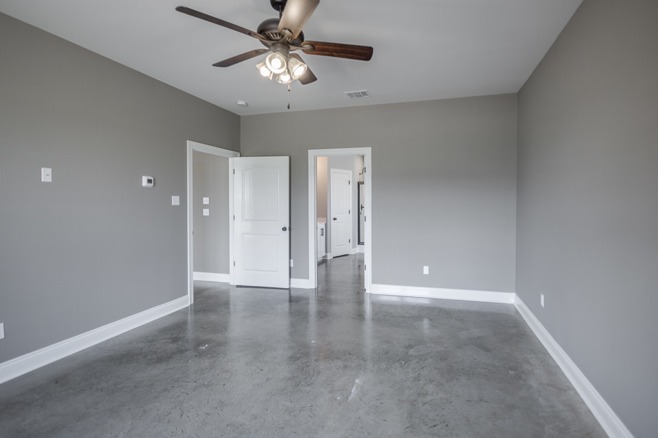 Mid-sized transitional master bedroom in New Orleans with grey walls, concrete floors and grey floor.