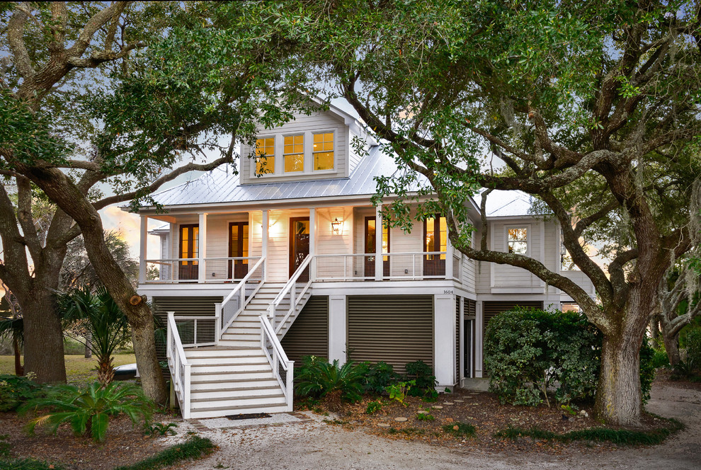 Design ideas for a large beach style two-storey white house exterior in Charleston with concrete fiberboard siding, a hip roof and a metal roof.