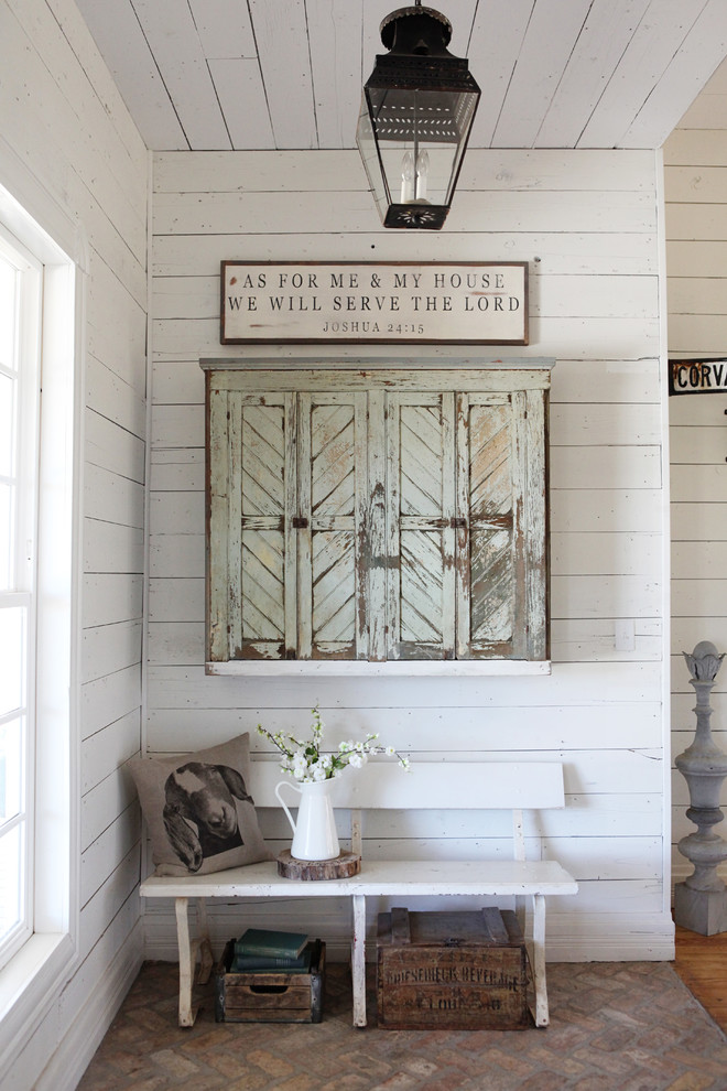 Photo of a mid-sized country entryway in Austin with white walls and brick floors.