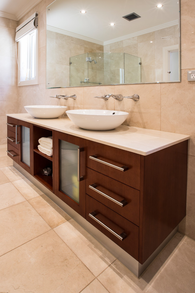 Photo of a mid-sized contemporary master bathroom in Sydney with flat-panel cabinets, medium wood cabinets, a corner shower, beige tile, porcelain tile, porcelain floors, a vessel sink, granite benchtops, beige floor and a hinged shower door.