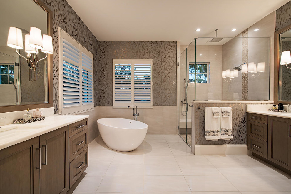 Inspiration for a large contemporary master bathroom in Miami with recessed-panel cabinets, medium wood cabinets, a freestanding tub, beige tile and marble benchtops.