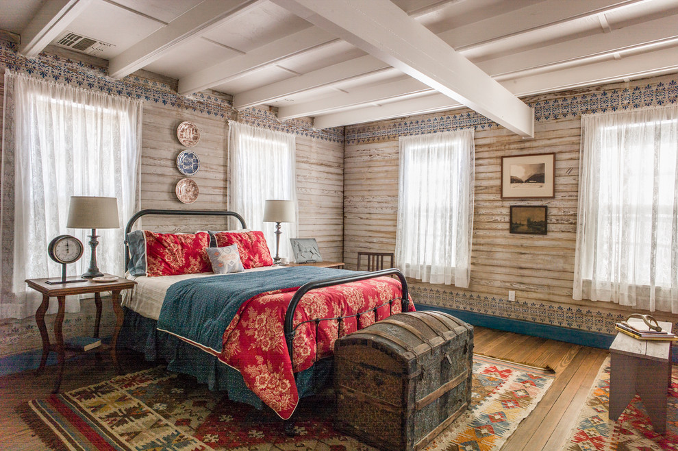 This is an example of a country bedroom in Austin with multi-coloured walls, dark hardwood floors and brown floor.