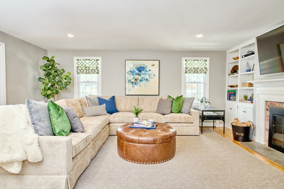 Design ideas for a large transitional open concept family room in Providence with a library, grey walls, light hardwood floors, a standard fireplace, a brick fireplace surround, a wall-mounted tv and beige floor.