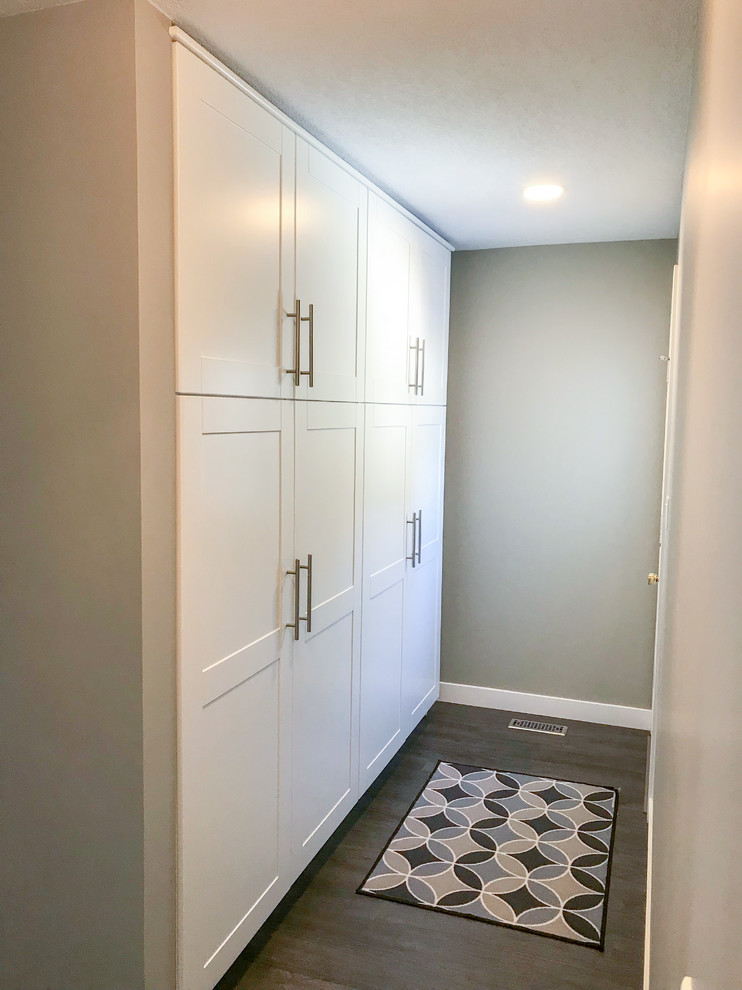 Photo of a modern built-in wardrobe in Edmonton with shaker cabinets, white cabinets, vinyl floors and brown floor.