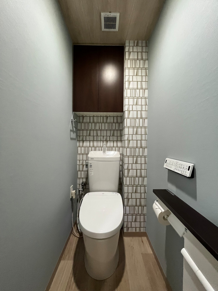 Design ideas for a scandinavian powder room in Tokyo with a one-piece toilet, blue walls, vinyl floors, brown floor, wallpaper and wallpaper.