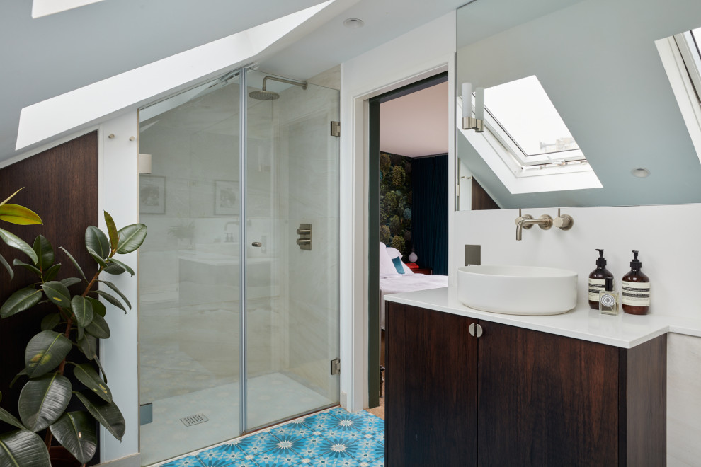 Photo of a small eclectic master bathroom in London with flat-panel cabinets, dark wood cabinets, a curbless shower, a wall-mount toilet, beige tile, porcelain tile, beige walls, cement tiles, a wall-mount sink, engineered quartz benchtops, blue floor, a hinged shower door, white benchtops, a niche, a single vanity and a floating vanity.