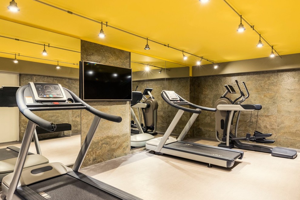 This is an example of a large contemporary home weight room in Paris with multi-coloured walls and linoleum floors.