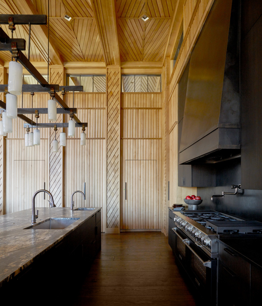 Example of a huge mountain style single-wall wood ceiling eat-in kitchen design with flat-panel cabinets, black cabinets, black backsplash, black appliances and an island