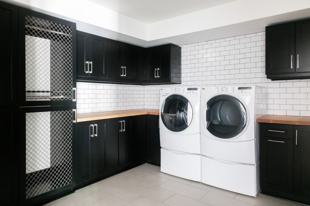 Photo of a mid-sized transitional laundry room in Atlanta with white walls, vinyl floors and black floor.