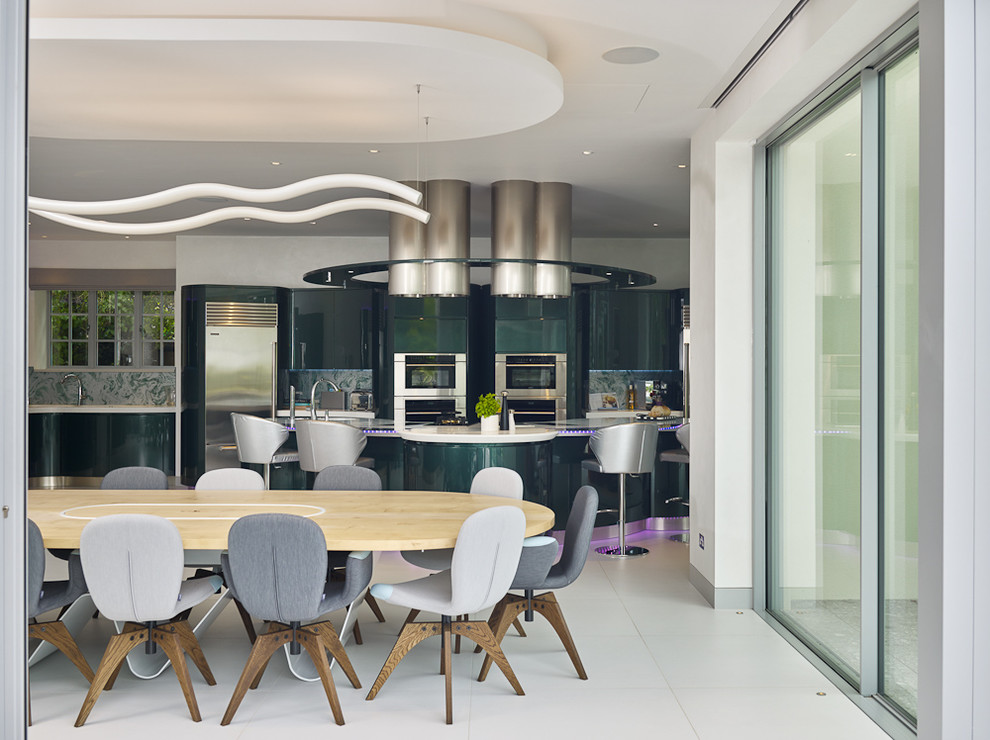 Design ideas for an expansive contemporary galley open plan kitchen in London with an integrated sink, flat-panel cabinets, green cabinets, quartz benchtops, green splashback, glass sheet splashback, stainless steel appliances, porcelain floors, with island and grey floor.