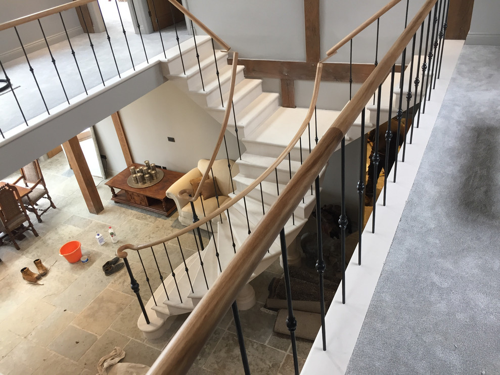 Photo of a large eclectic limestone floating staircase in Other with limestone risers and metal railing.