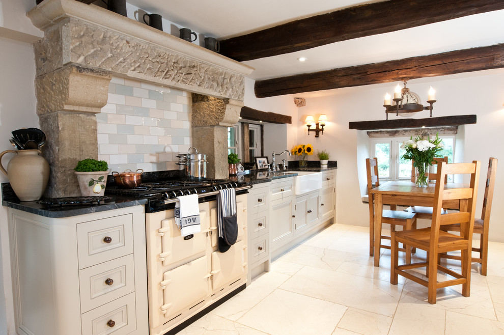 Mid-sized country eat-in kitchen in Other with a farmhouse sink, beaded inset cabinets, granite benchtops, porcelain splashback, limestone floors, no island and white appliances.