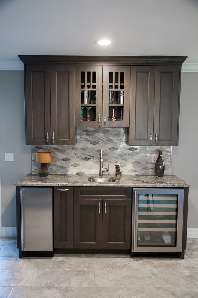 Design ideas for a large transitional l-shaped home bar in Tampa with an undermount sink, shaker cabinets, dark wood cabinets, granite benchtops, stone tile splashback and porcelain floors.