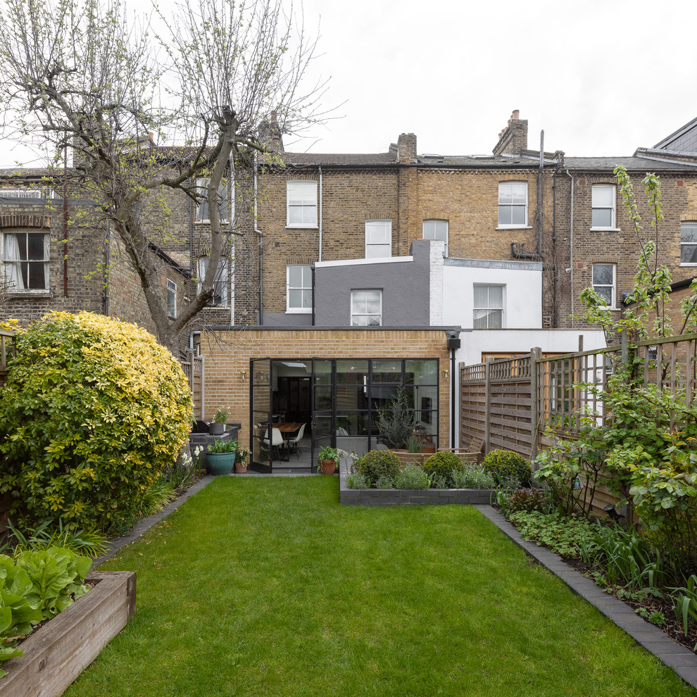 Mid-sized contemporary one-storey brick beige townhouse exterior in London with a flat roof and a mixed roof.