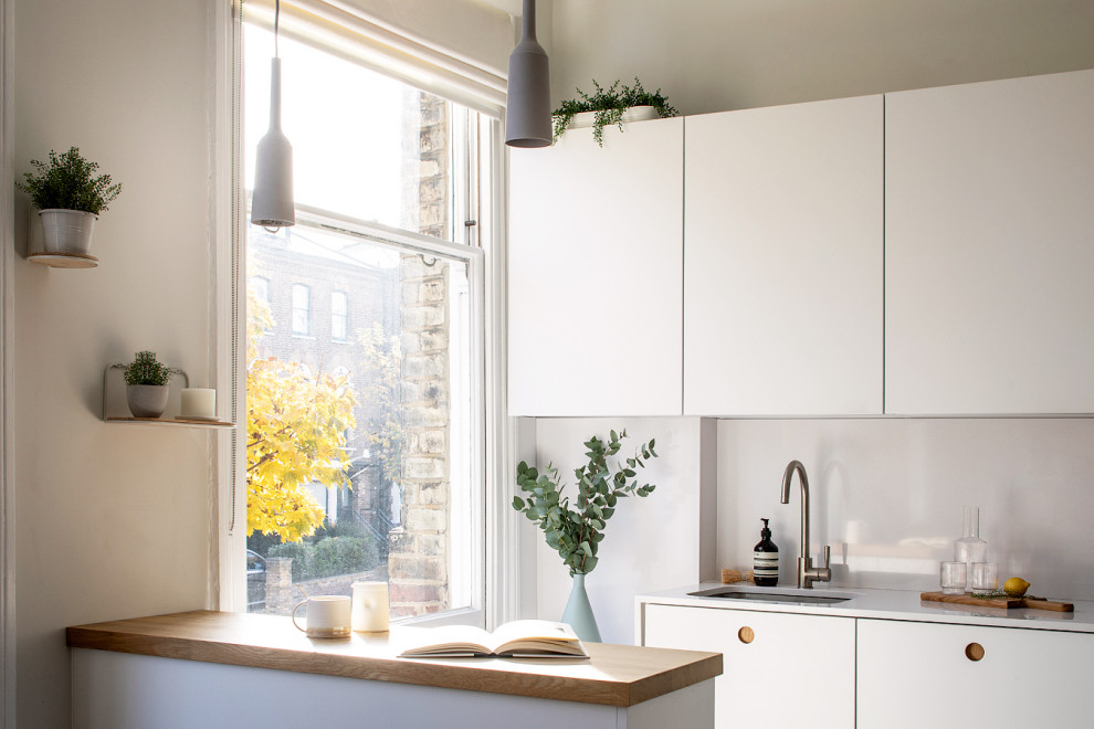 This is an example of a small modern l-shaped kitchen in London with an undermount sink, flat-panel cabinets, quartzite benchtops, white splashback, engineered quartz splashback, panelled appliances, ceramic floors, a peninsula, grey floor and white benchtop.