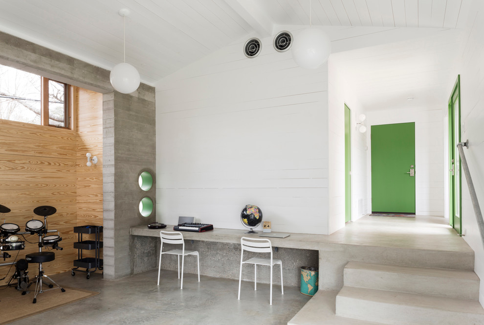 This is an example of a mid-sized contemporary home studio in Austin with white walls, concrete floors, no fireplace, a built-in desk and grey floor.