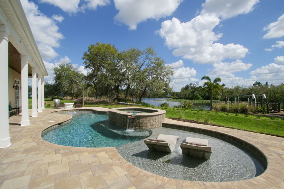 This is an example of a large beach style backyard custom-shaped pool in Other with concrete pavers and a hot tub.