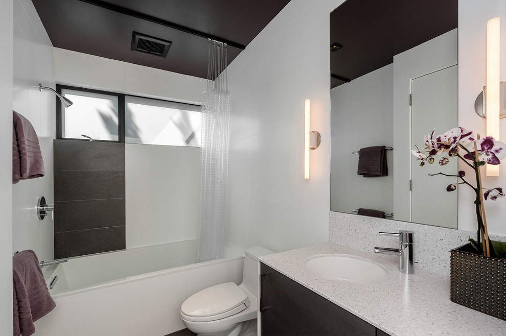 Photo of a modern bathroom in San Francisco with an undermount sink, dark wood cabinets, an alcove tub, a shower/bathtub combo, a one-piece toilet and white tile.