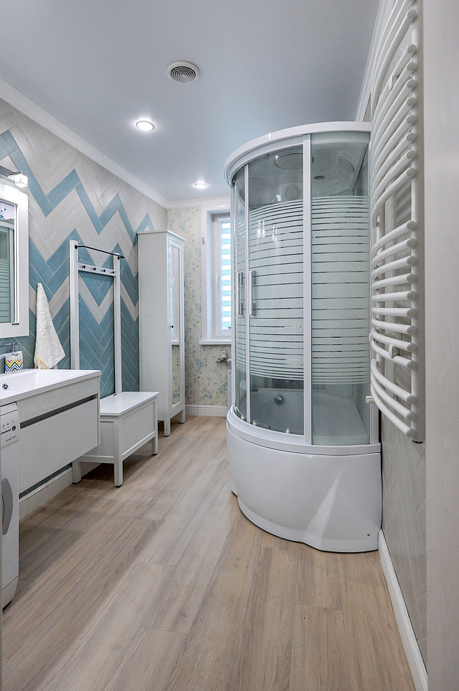This is an example of a mid-sized country bathroom in Other with flat-panel cabinets, white cabinets, a wall-mount toilet, multi-coloured tile, porcelain tile, vinyl floors, a wall-mount sink, solid surface benchtops, beige floor, white benchtops, a floating vanity and wallpaper.