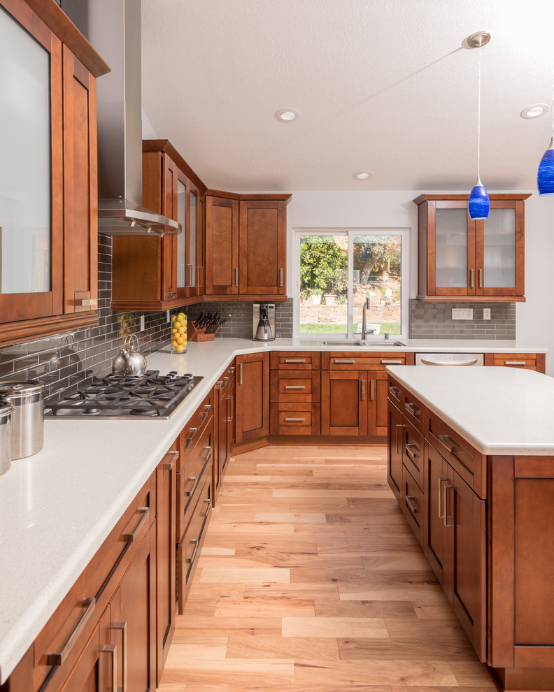 Large contemporary u-shaped eat-in kitchen in San Diego with an undermount sink, shaker cabinets, medium wood cabinets, quartz benchtops, grey splashback, subway tile splashback, stainless steel appliances, light hardwood floors and with island.