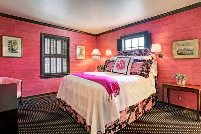 This is an example of a traditional guest bedroom in Houston with pink walls and carpet.