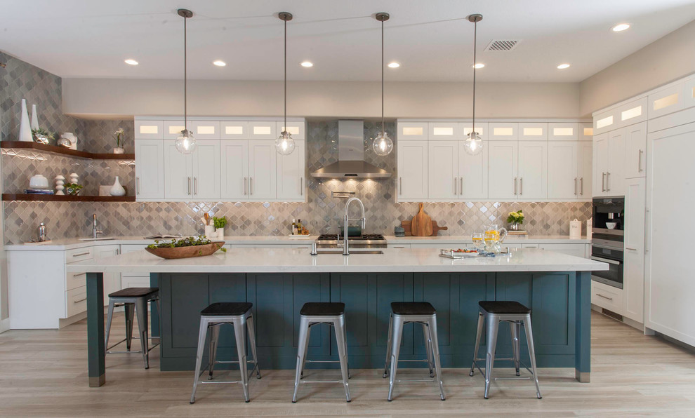 Design ideas for a large transitional u-shaped eat-in kitchen in San Diego with an undermount sink, recessed-panel cabinets, white cabinets, quartz benchtops, grey splashback, glass tile splashback, stainless steel appliances, light hardwood floors, with island, beige floor and white benchtop.