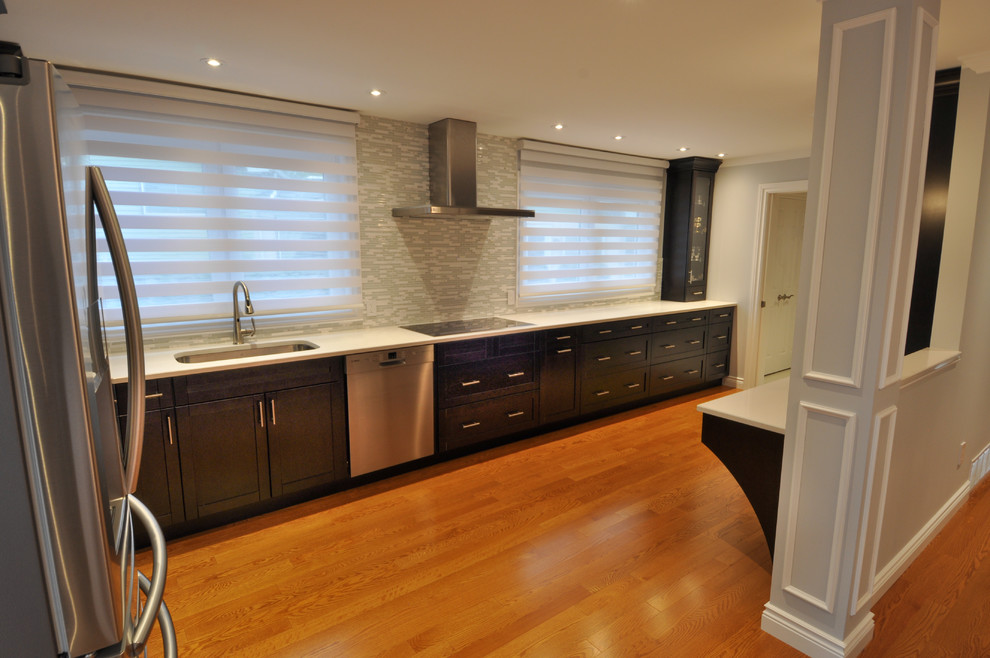 Large transitional galley light wood floor enclosed kitchen photo in Toronto with a single-bowl sink, shaker cabinets, dark wood cabinets, quartzite countertops, beige backsplash, stone tile backsplash, stainless steel appliances and an island