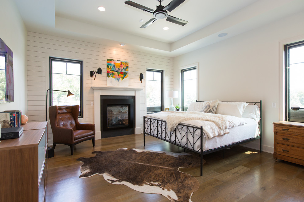 Design ideas for a country master bedroom in Omaha with white walls, a standard fireplace, medium hardwood floors and brown floor.