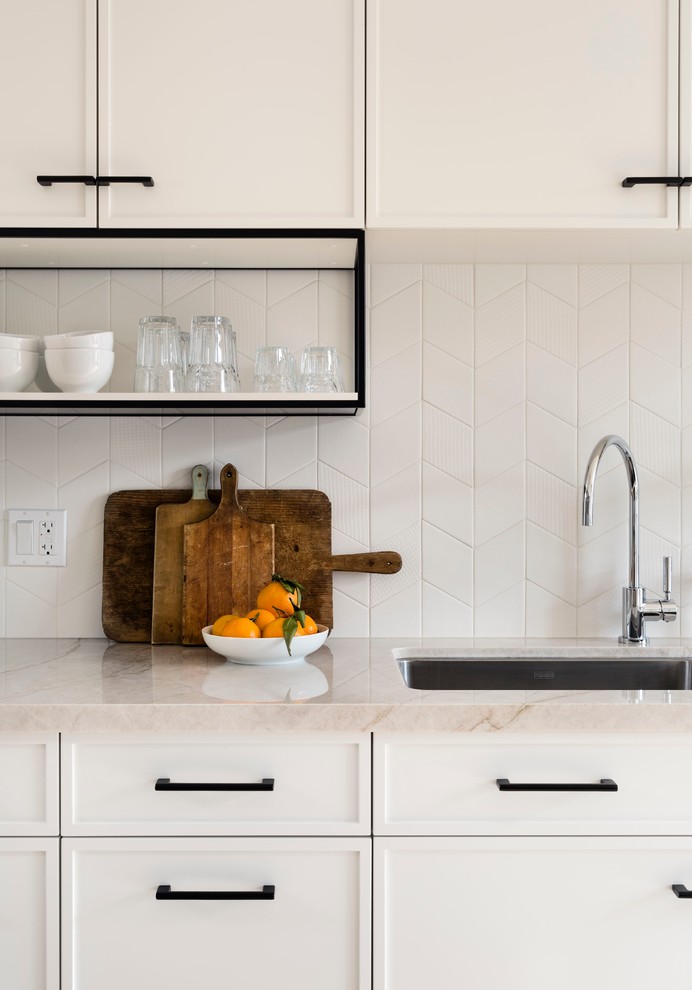 Example of a mid-sized transitional galley light wood floor enclosed kitchen design in Toronto with an undermount sink, recessed-panel cabinets, white cabinets, quartzite countertops, white backsplash, ceramic backsplash, stainless steel appliances and a peninsula