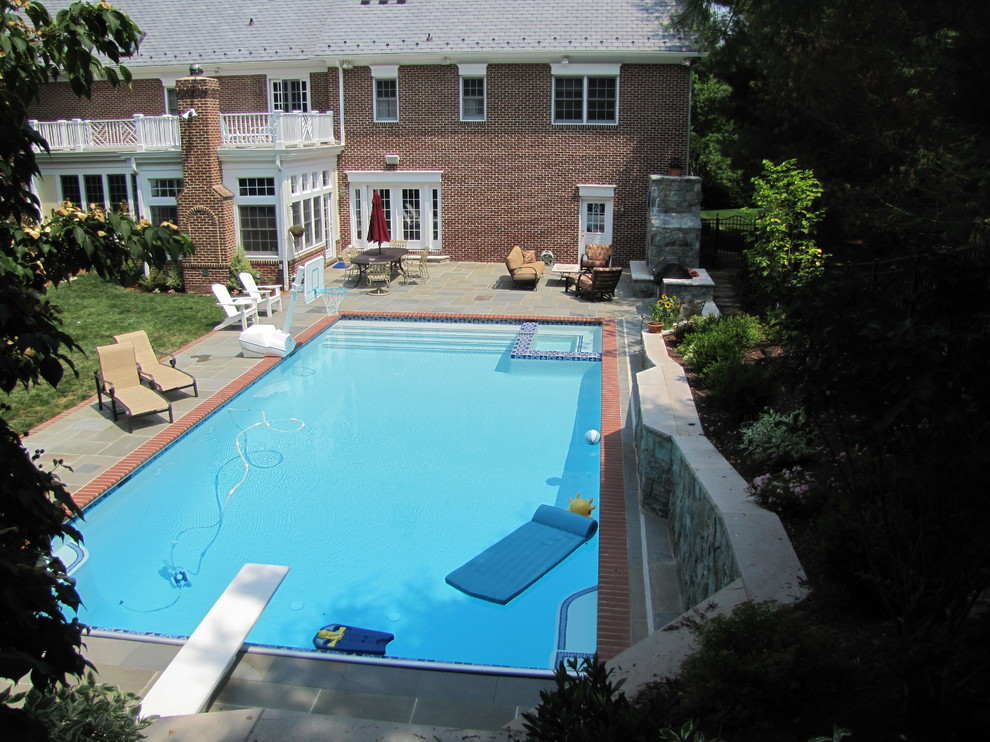 Photo of a large traditional backyard rectangular pool in DC Metro with natural stone pavers and a hot tub.