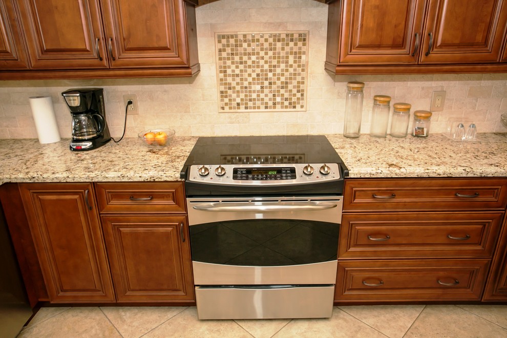 Mid-sized transitional u-shaped porcelain tile eat-in kitchen photo in Miami with an undermount sink, raised-panel cabinets, brown cabinets, granite countertops, beige backsplash, stone tile backsplash, stainless steel appliances, beige walls and a peninsula