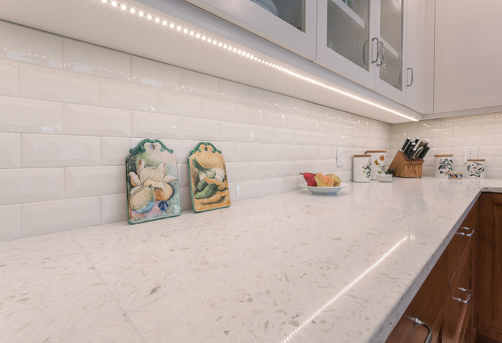 Example of a transitional light wood floor home design design with a double-bowl sink, shaker cabinets, quartz countertops, white backsplash, subway tile backsplash and stainless steel appliances