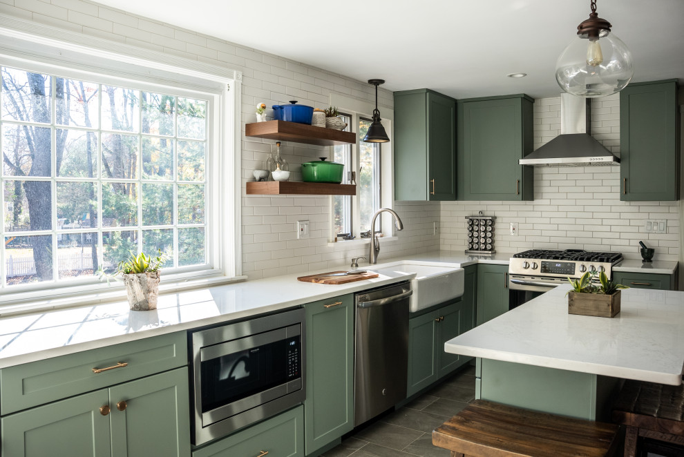 Expansive transitional galley kitchen in Boston with a farmhouse sink, flat-panel cabinets, green cabinets, quartzite benchtops, white splashback, ceramic splashback, stainless steel appliances, vinyl floors, with island, brown floor and white benchtop.