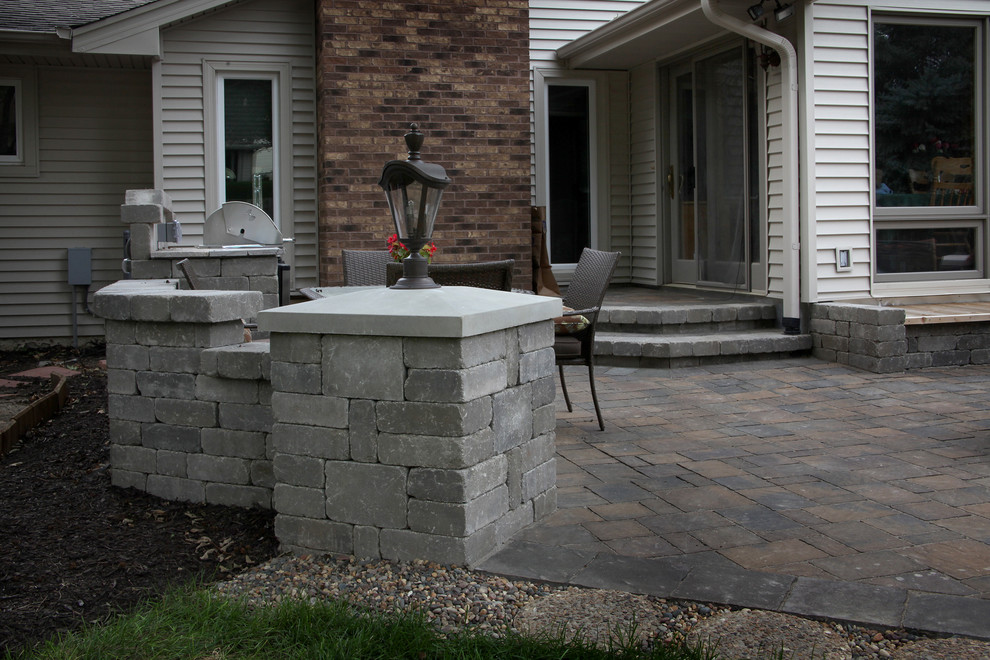 This is an example of a large traditional backyard patio in Omaha with a fire feature, concrete pavers and no cover.