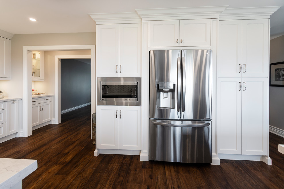 Eat-in kitchen - large transitional u-shaped dark wood floor and brown floor eat-in kitchen idea in Toronto with an undermount sink, recessed-panel cabinets, white cabinets, quartz countertops, white backsplash, ceramic backsplash, stainless steel appliances, an island and white countertops