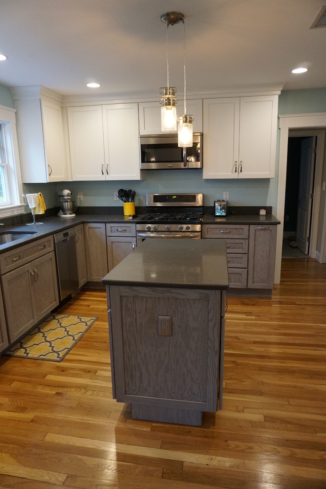 Inspiration for a mid-sized transitional u-shaped medium tone wood floor eat-in kitchen remodel in Boston with an undermount sink, shaker cabinets, gray cabinets, quartz countertops, black backsplash, stainless steel appliances and an island
