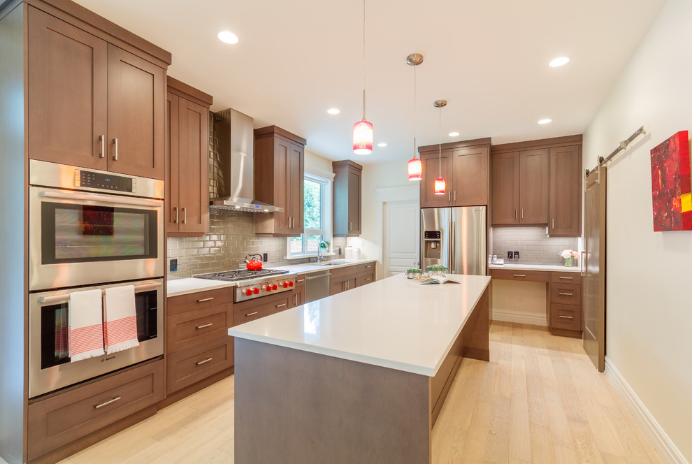Photo of a modern l-shaped eat-in kitchen in Vancouver with a double-bowl sink, shaker cabinets, medium wood cabinets, quartzite benchtops, beige splashback, glass tile splashback, stainless steel appliances, light hardwood floors and with island.