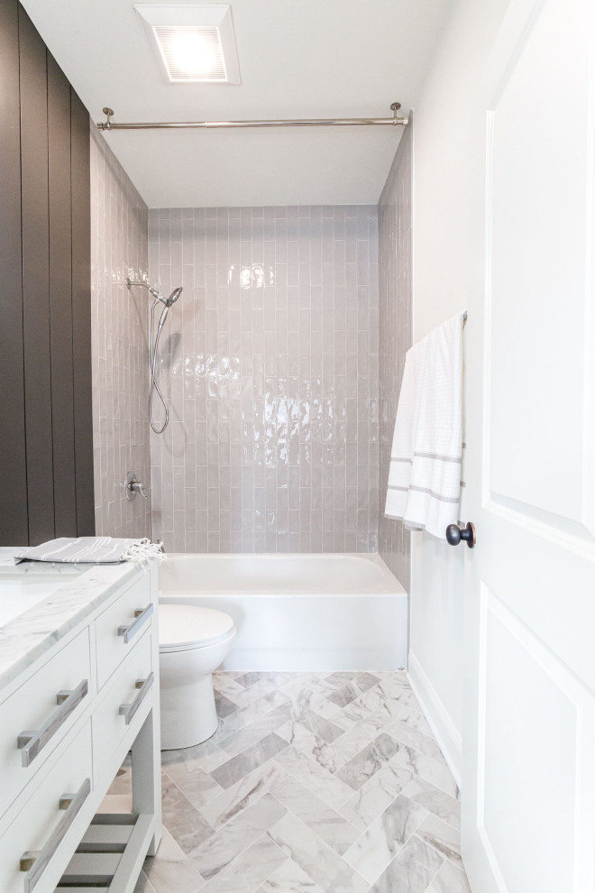 Photo of a mid-sized contemporary kids bathroom in Atlanta with shaker cabinets, white cabinets, a shower/bathtub combo, a one-piece toilet, gray tile, porcelain tile, white walls, marble floors, an undermount sink, marble benchtops, grey floor, a shower curtain, white benchtops, a niche, a single vanity, a freestanding vanity and planked wall panelling.